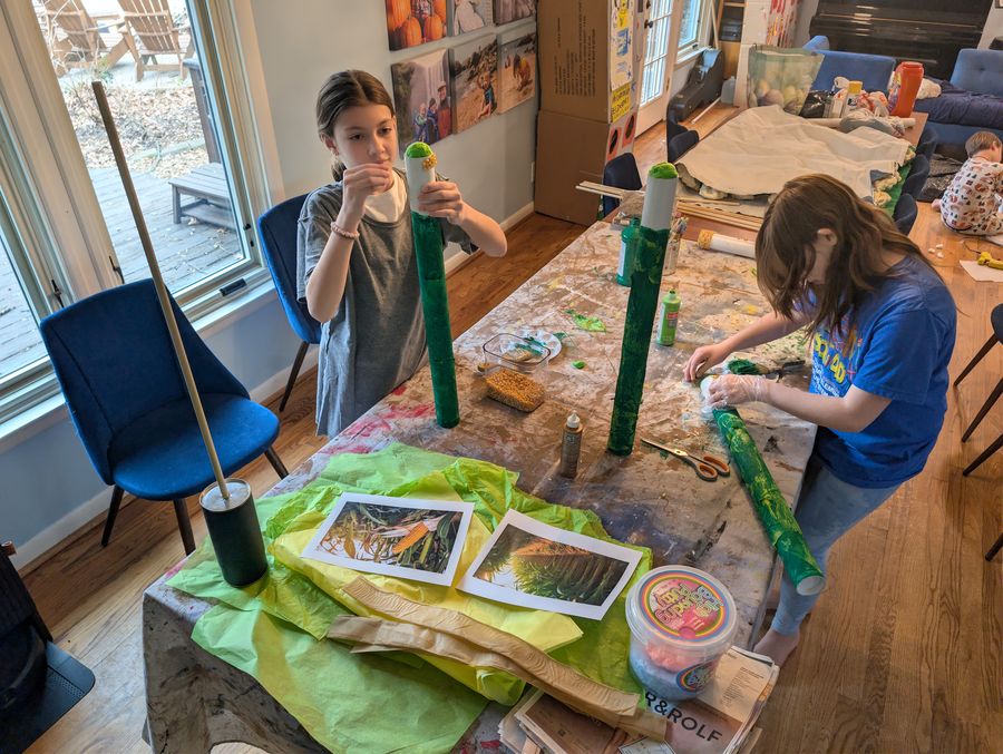 Kids building and painting set pieces at the kitchen table