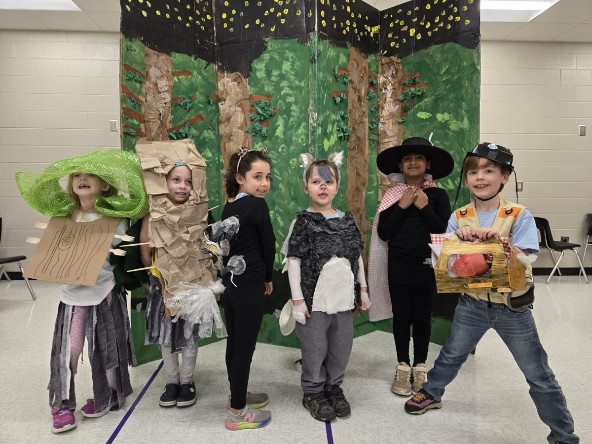 Six kids in handmade forest-themed costumes in front of a painted backdrop